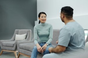 A woman and a man are sitting on a couch in a modern, minimalist living room.